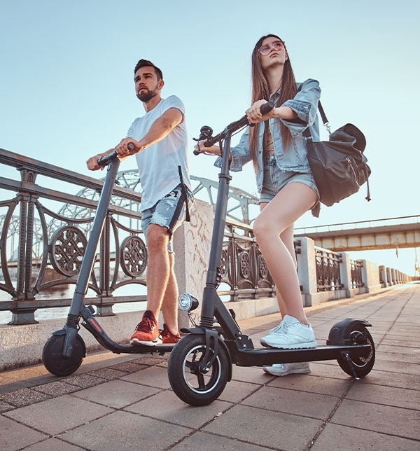 Choisissez le NVEI, l'avenir de la mobilité urbaine pour la SMENO couple en trottinette électrique circulant en ville - Avec la SMENO, déplacez vous en NVEI en toute sécurité avec l'assurance NVEI