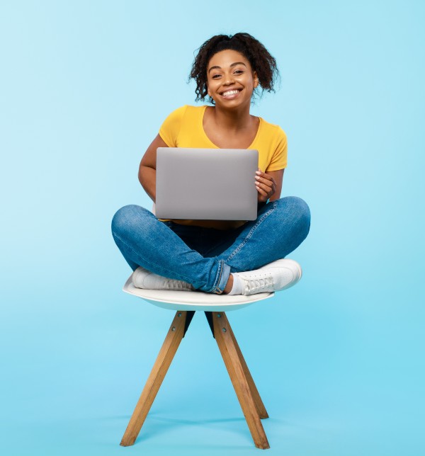 Vous cherchez une mutuelle parfaite pour votre situation de boursier - ça se passe ici ! Etudiante assise sur une chaise avec son ordinateur - La SMENO vous dit tout sur les mutuelles pour étudiants boursiers