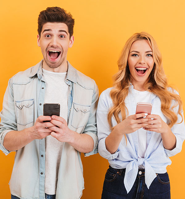 Assurez votre colocation avec bail collectif avec la SMENO Deux étudiants souriant se servant de leur téléphone - La SMENO assure votre colocation en cas de bail collectif