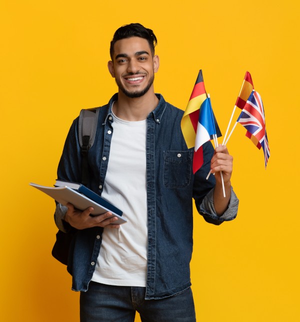 Homme tenant des drapeaux et ses affaires pour étudier - La SMENO vous conseille les 5 meilleures destinations pour vos études à l'étranger