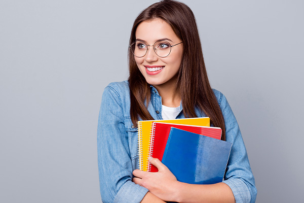 Soyez serein dans votre recherche de job lycéen, la SMENO vous aide lycéenne souriante portant ses manuels scolaires - La SMENO aide les lycéens à trouver un job
