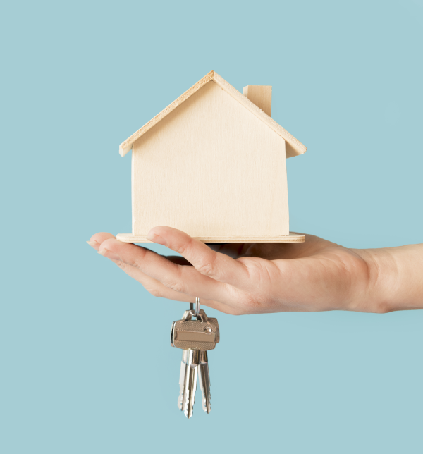 Main tenant une maison en bois miniaturisée et une paire de clés - Changez d'assurance habitation en cours d'année, c'est possible !